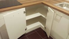 an empty corner in a kitchen next to a sink and counter top with no drawers