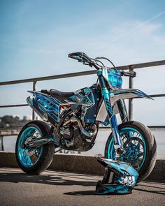 a blue and black motorcycle parked on the side of a road next to a body of water