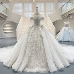 a white wedding dress on display in a museum with other gowns and dresses behind it