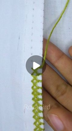 someone is stitching on the side of a piece of fabric with green yarn and thread