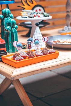 an orange tray with cupcakes on it sitting on a table next to other dessert items