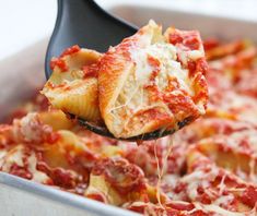 a spatula full of cheese and sauce being lifted from a casserole dish