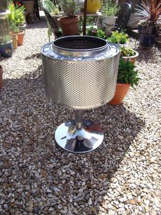 a potted plant sitting on top of a metal stand in the middle of gravel