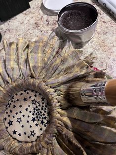 a close up of a flower on a table with paint and brushes in the background