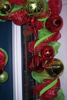 a red and green christmas wreath on the front door with ornaments hanging from it's sides