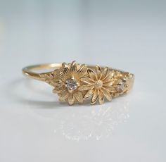 This dainty daisy ring is a beautiful little stacking ring that is like a little bouquet of gold flowers and diamonds wrapped around your fingers. This ring is made in solid 14 karat gold with and set with two genuine VS-SI white diamonds. Gentle Daisies embody many meanings, from joy to good luck and new beginnings. In Victorian times, they were taken to represent loyalty and trust. Innocent daisies are a simple flower with many meanings, and are a perfect daily ring companion, sure to make you Gold Daisy Ring, Dainty Gold Flower Stackable Rings, Delicate Stackable Yellow Gold Flower Ring, Delicate Yellow Gold Stackable Flower Ring, Dainty Stackable Flower Ring For Wedding, Delicate Flower Stackable Rings For Anniversary, Dainty Yellow Gold Flower Diamond Ring, Dainty Flower Midi Rings For Wedding, Dainty Yellow Gold Cluster Ring