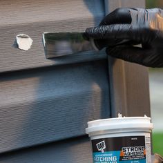 a person in black gloves painting the outside of a house