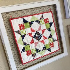 a close up of a quilt hanging on a wall in a frame with chicken wire