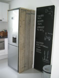 a kitchen with a refrigerator and chalkboard on the wall next to it's door