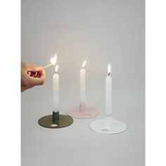 three white candles with one lit in the middle