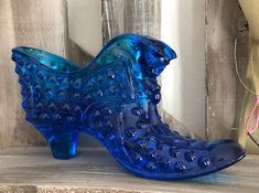 a blue glass shoe sitting on top of a wooden shelf