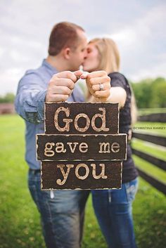 a man and woman kissing in front of a wooden sign that says god gave me you