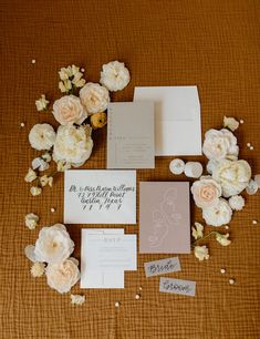 the wedding stationery is laid out on top of the bed with flowers and cards