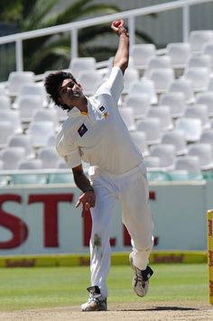 a man in white uniform throwing a red ball