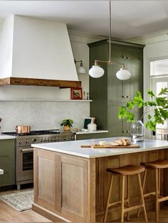 a kitchen with two stools and an island in the middle of it, surrounded by greenery