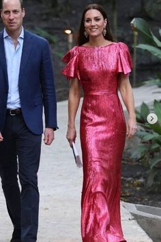 the duke and person are walking together in red dresses, one is wearing a blue suit