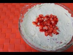 a bowl filled with white frosting and strawberries on top of an orange mat