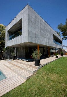 the house is made out of concrete and has a large pool in front of it