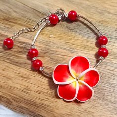 a red and white flower bracelet on a wooden table