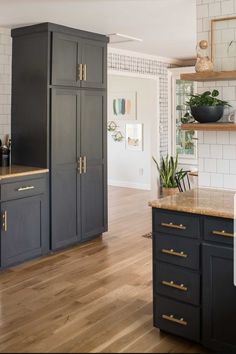 a kitchen with wooden floors and black cabinets