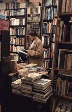 a woman standing in front of a bookshelf filled with lots of book's