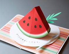 a piece of paper with a watermelon cut out of it sitting on top of a card