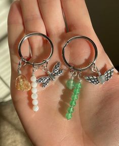 two small key chains are attached to the back of a pair of hoop earrings with beads and charms