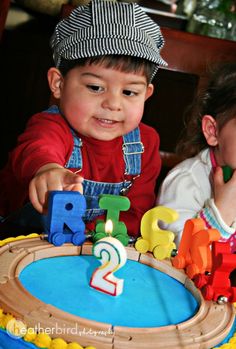 two young children sitting in front of a birthday cake with the number 2 on it