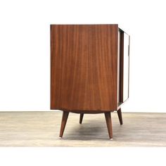 a wooden cabinet sitting on top of a hard wood floor next to a white wall