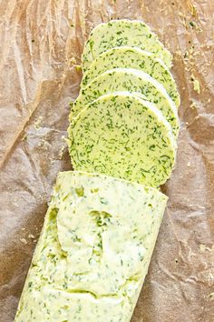 sliced slices of bread with cheese and herbs on top, sitting on wax paper next to each other