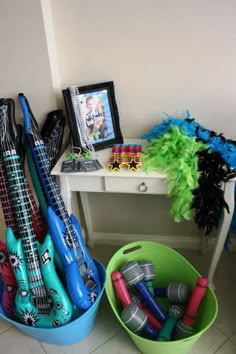 there are many guitars in buckets on the floor next to a table with pictures