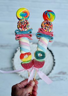 a hand holding two candy lollipops with sprinkles on them