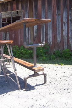 an old wooden bench sitting in front of a building with metal pipes and ladders