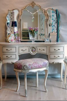 a white dressing table with a mirror and stool next to it on a hard wood floor