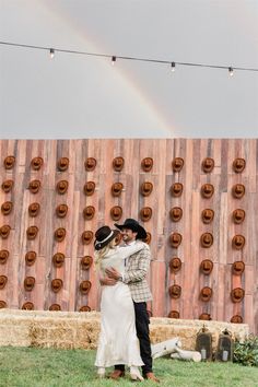 a man and woman standing next to each other in front of a wooden wall with circles on it