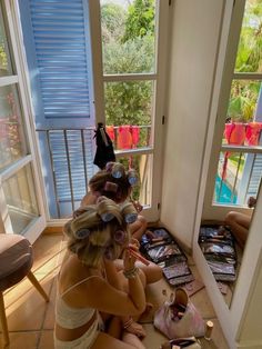 two women are sitting on the floor in front of a window and one is brushing her hair