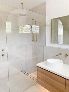 a bathroom with a glass shower door, sink and mirror on the wall next to it