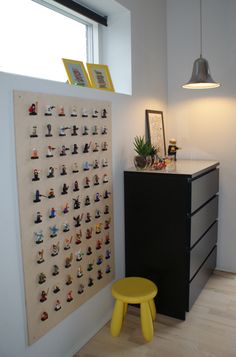 a yellow stool sits in front of a wall with legos on the pegboard