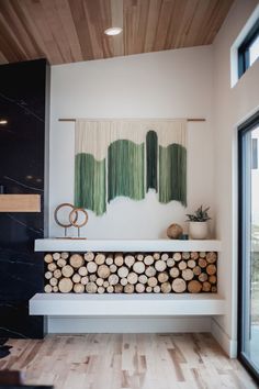 a fireplace with logs stacked on top of it in front of a painting and window