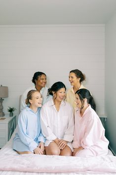 a group of women sitting on top of a bed next to each other in pajamas