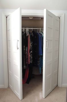 an open closet with clothes hanging on hangers