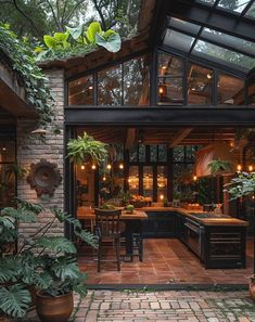 an outdoor kitchen and dining area is lit up by lights on the ceiling, surrounded by greenery