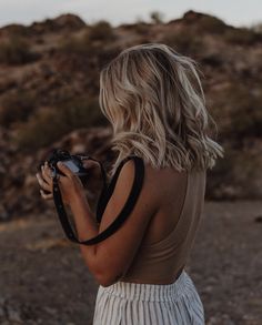 a woman standing in the desert holding a camera