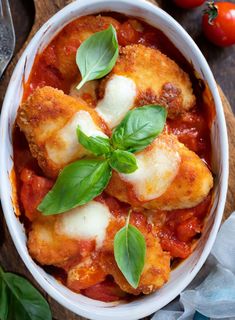 a white bowl filled with ravioli and sauce on top of a wooden cutting board