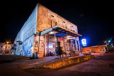 an old building is lit up at night with graffiti on the walls and outside it