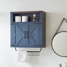 a blue cabinet hanging on the wall next to a mirror and toilet paper dispenser