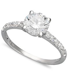 a white gold ring with diamonds on the band and a round cut diamond in the center