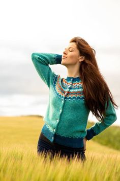 a woman standing in tall grass with her hands on her head and looking up at the sky