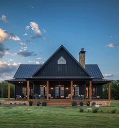 a large black house sitting on top of a lush green field