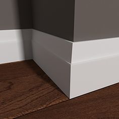 the corner of a room with wood flooring and white trim on it's walls